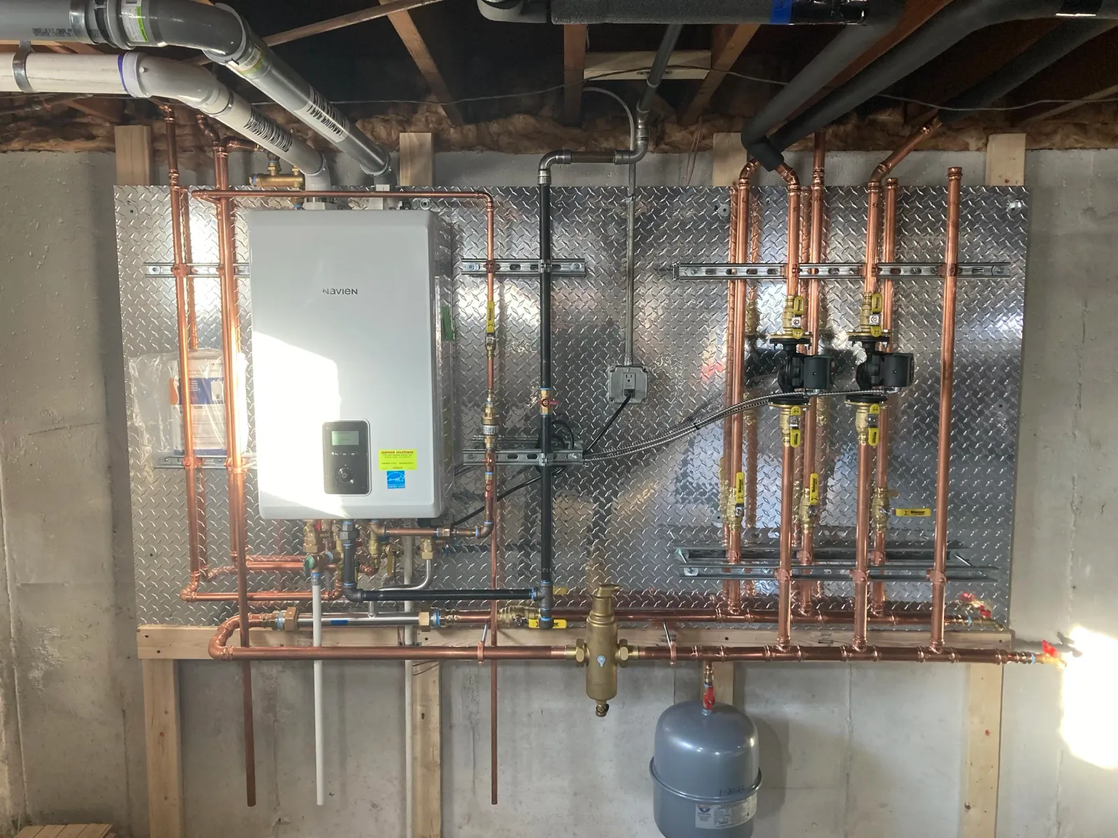 Service Solutions Plumbing Navien boiler installation with copper piping and heating zones in Massachusetts
