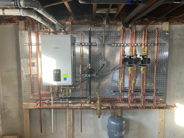 Service Solutions Plumbing Navien boiler installation with copper piping and heating zones in Massachusetts