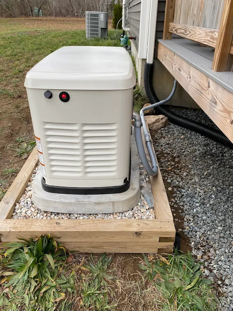 Standby generator installed on a pad beside a house with conduit run back to the electrical service