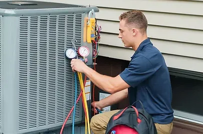 HVAC technician using gauges to service an outdoor air conditioning unit for efficient cooling performance.