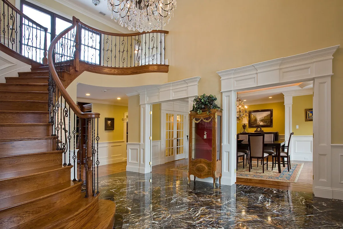 Grand Entrance Residence — polished marble floor foyer with curved staircase and chandelier. Boston area.