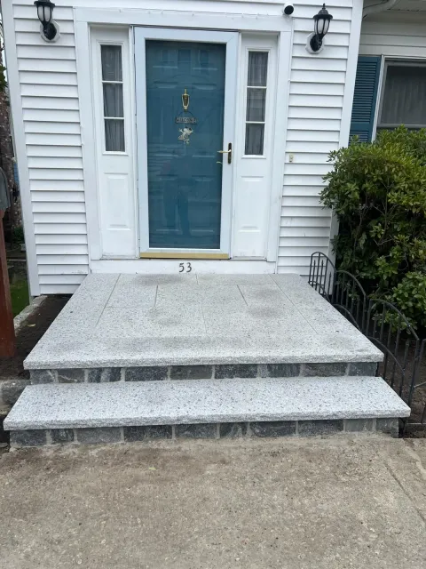 Front entrance with blue door and concrete steps leading up to a white house