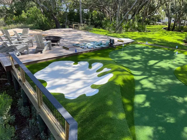 Backyard synthetic turf putting green with white bunker and deck seating in Sea Island, Georgia