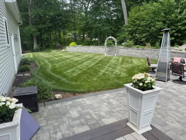 Freshly mowed landscaped backyard beside a patio with visible mowing pattern