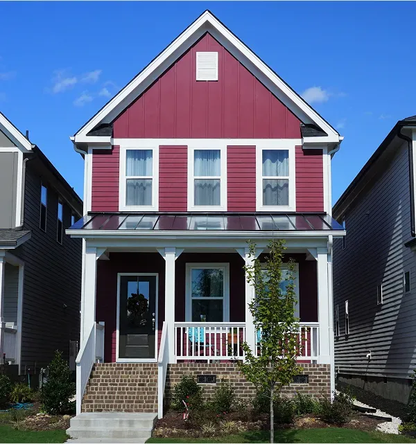 A two-story residential house, painted in a vibrant red, with a welcoming main entrance and a well-kept front garden featuring a leafy tree, adding a natural and homely touch.