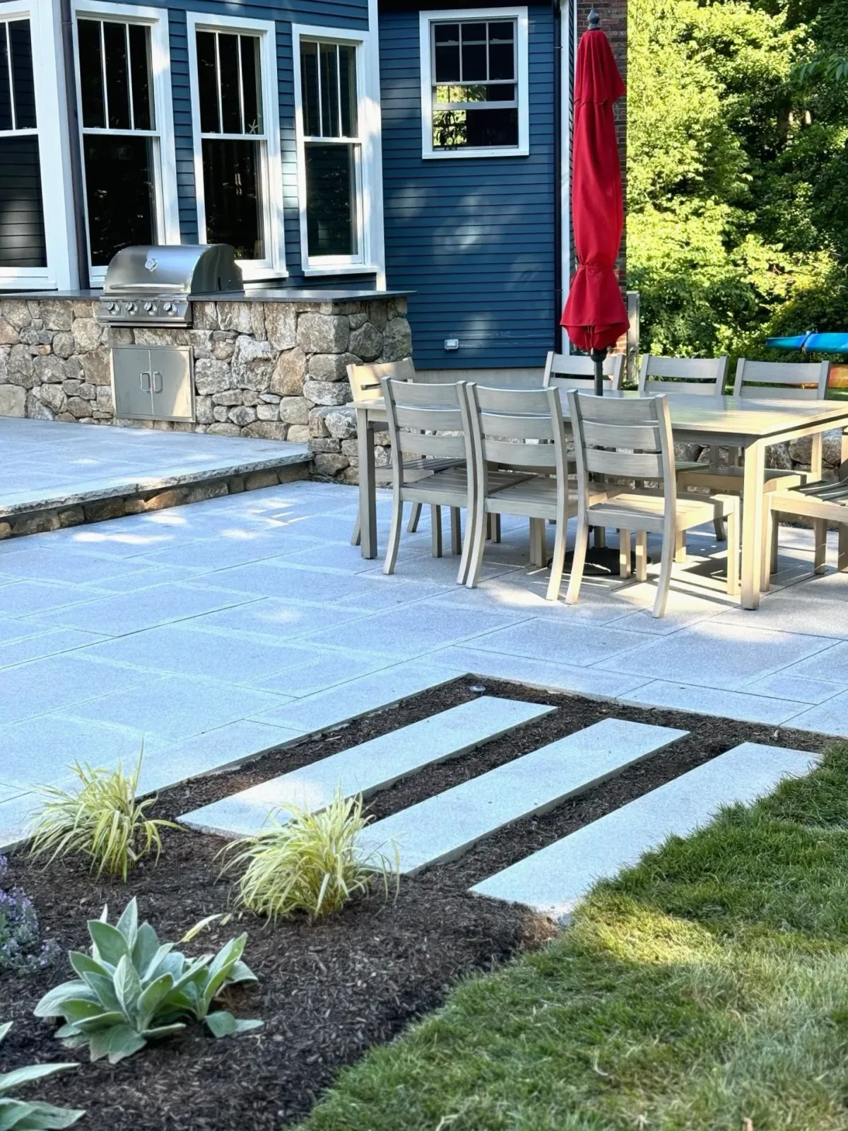 Stone work in the way of patio grill station and granite pavers create an outdoor dining space that is the focus of three season outdoor entertaining.