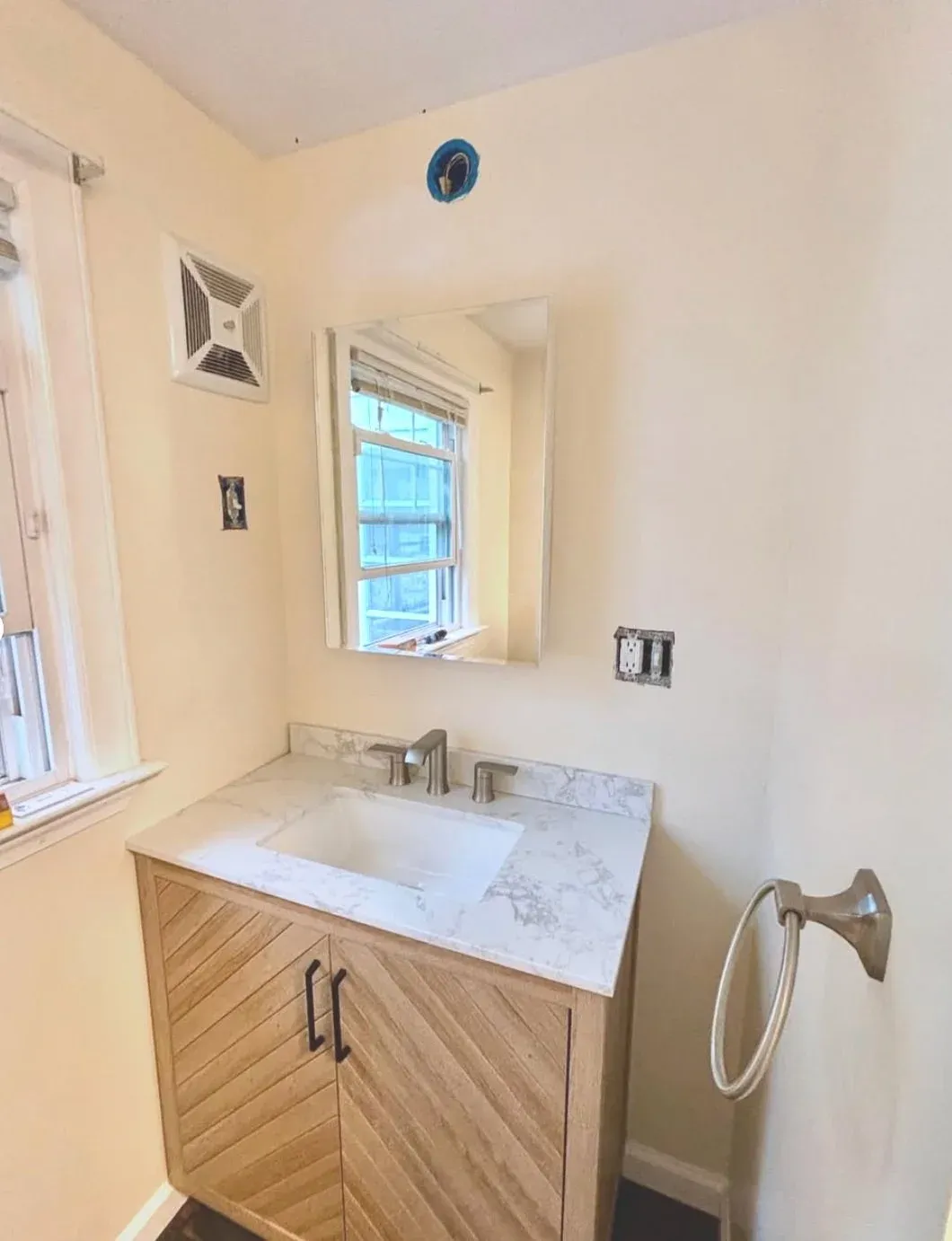 Bathroom vanity with marble countertop, mirror, and sink