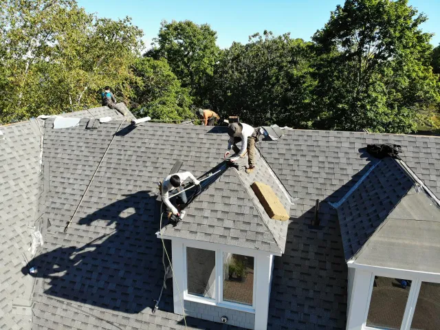 Roofing Company Workers Perched on Eaves While Installing New Roof