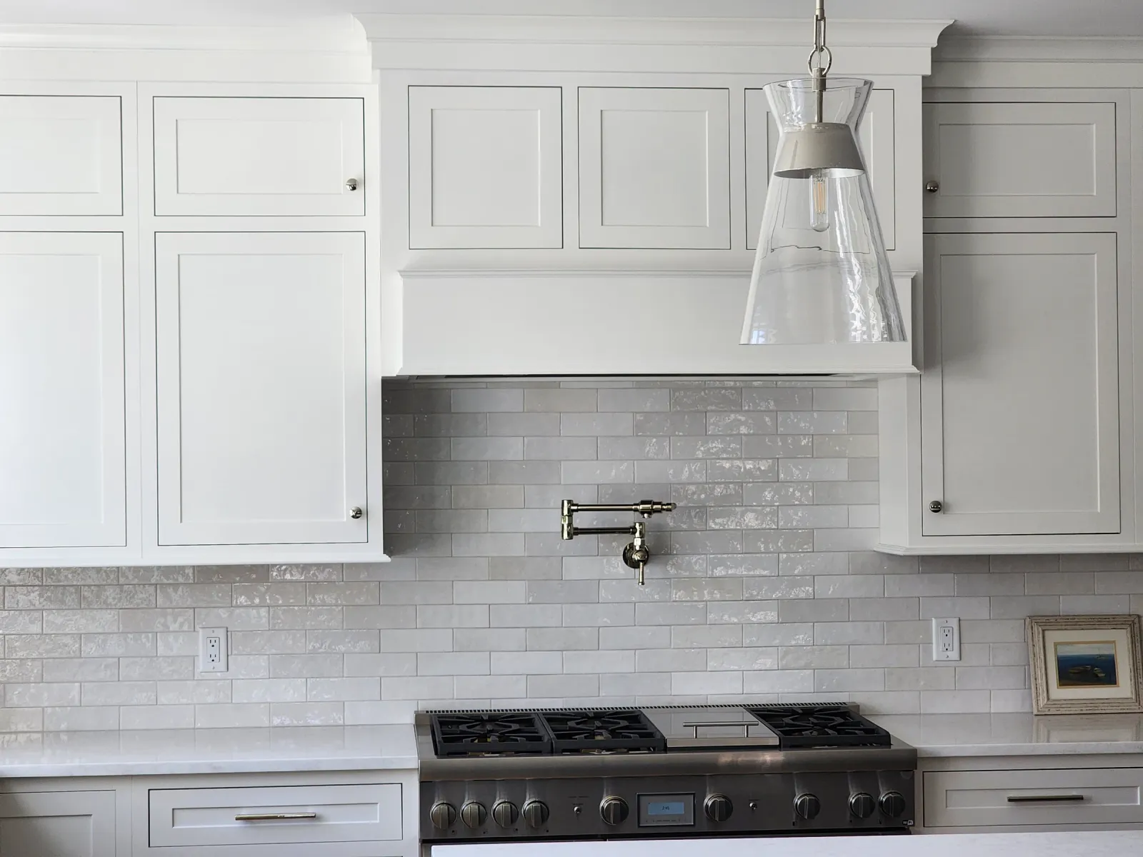 White kitchen backsplash surrounding a range beneath a pendant light