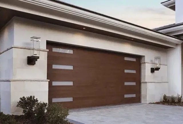 Brown wooden garage door with horizontal frosted glass accents, flanked by sconces.