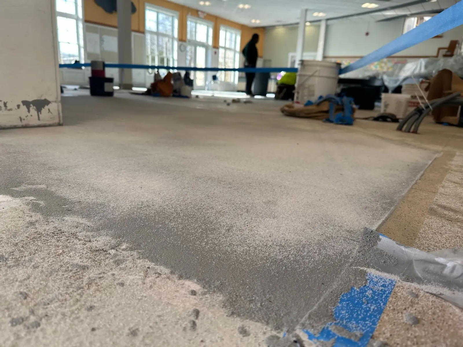 Partially finished office interior with exposed floor, workers, and construction materials