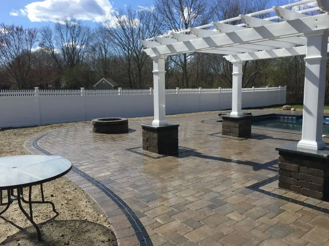 A patio with a pergola and a table and chairs