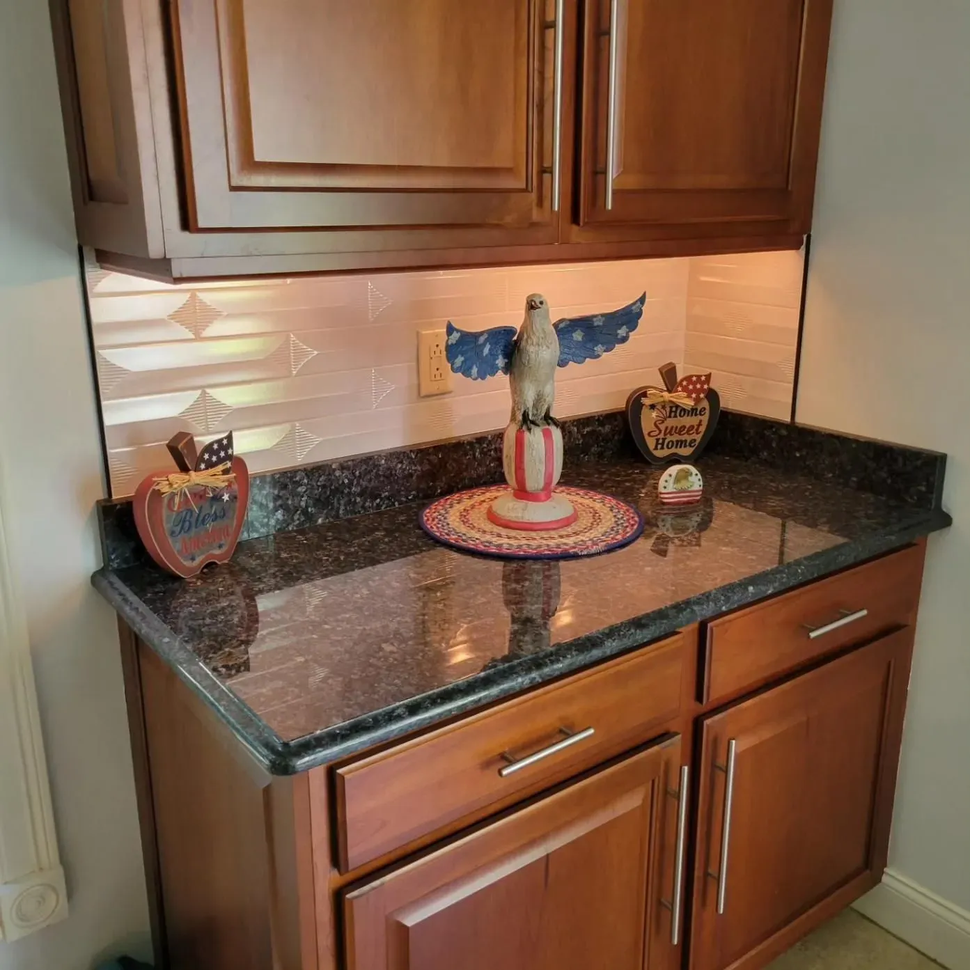 Kitchen corner counter with dark granite, wooden cabinets, and decorative bird figurines.