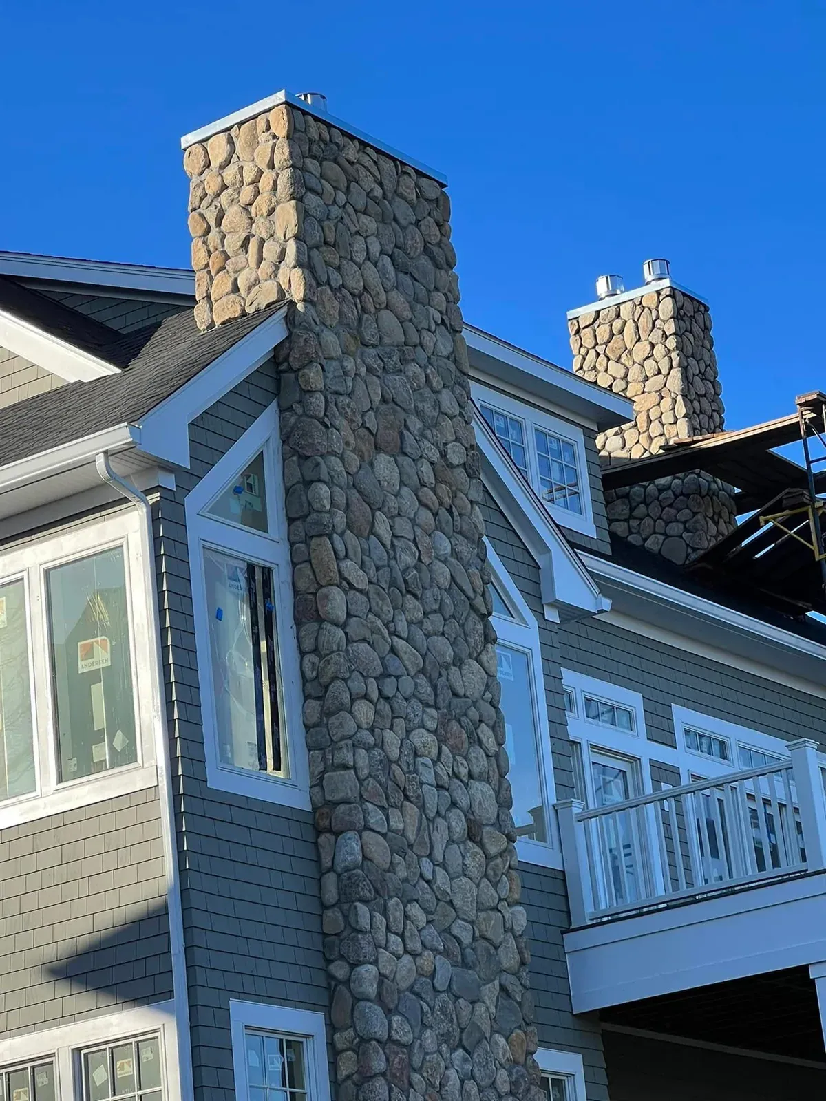 Natural stone chimney rising along the side of a coastal home