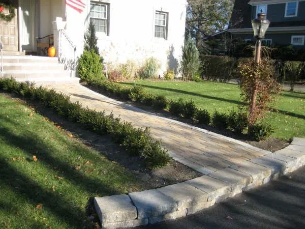 A walkway leading to a house with a flag in the background