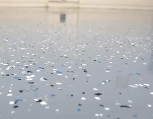 Close-up of a shiny surface with scattered black, white, and blue confetti.
