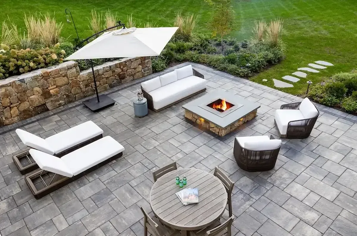 aerial view of a custom stone patio with 2 lounge chairs, umbrella, and fire pit.