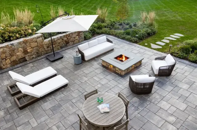aerial view of a custom stone patio with 2 lounge chairs, umbrella, and fire pit.