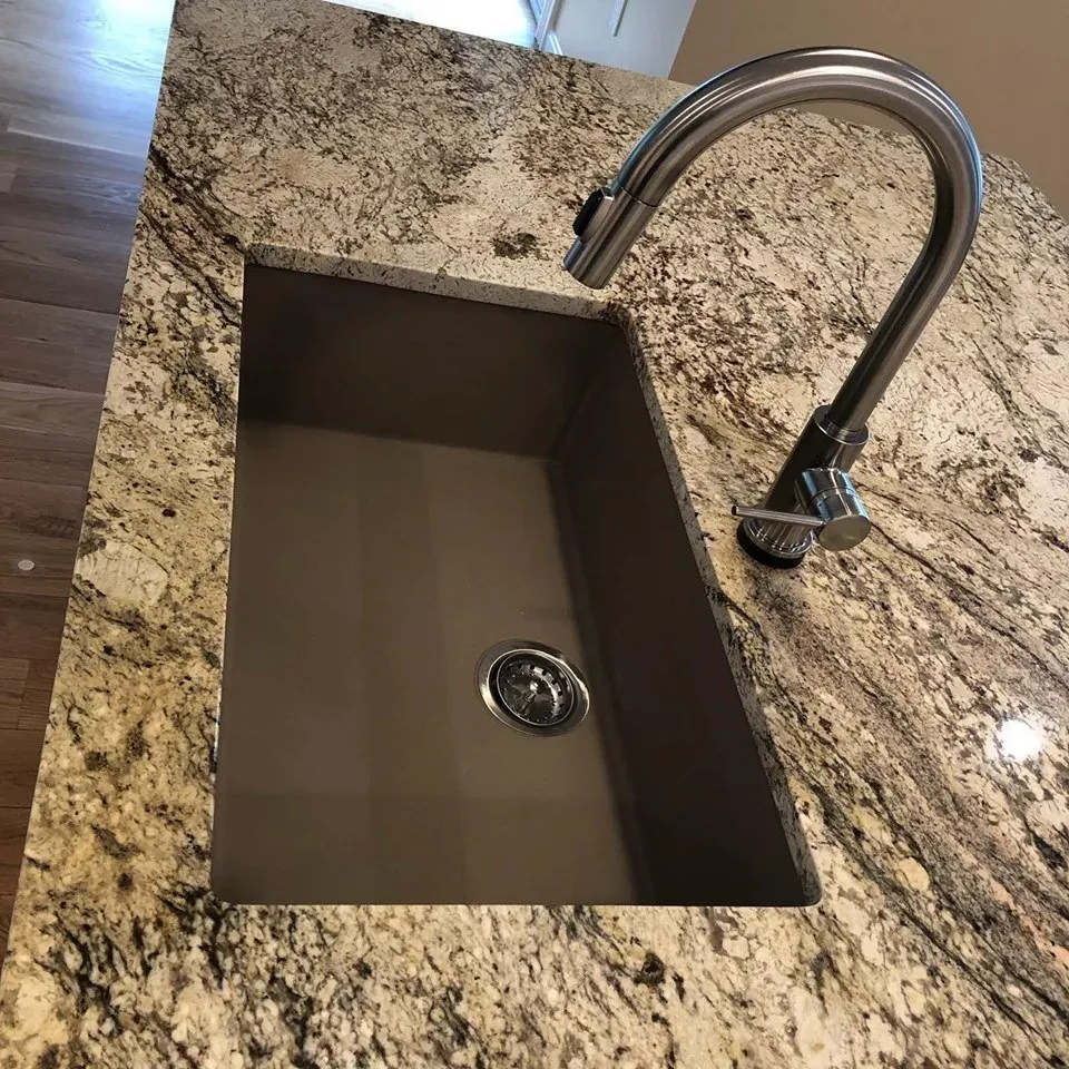 A kitchen sink with a faucet on a granite counter top