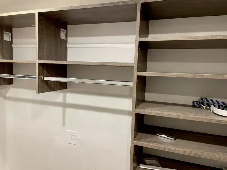 Built-in closet shelving with empty shelves in a beige room, plus a few small items on the right.