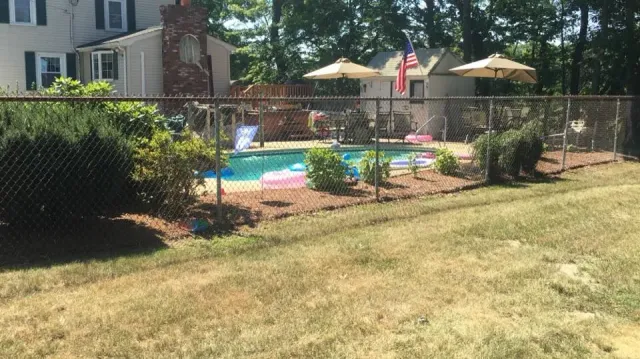 a chain link fence surrounds a swimming pool in a backyard