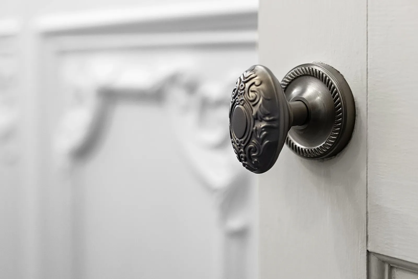 Close-up of a decorative metal doorknob on a white cabinet door