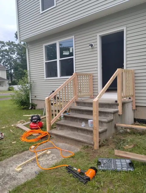 Newly built wooden stairs with railings leading to a house door.