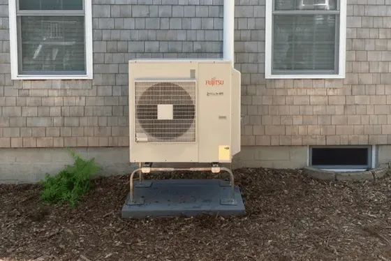 A large air conditioner is sitting on the side of a house.