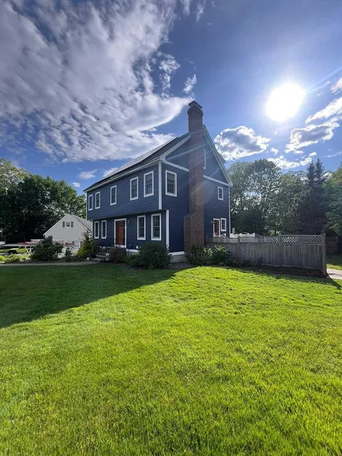 A large blue house with a large lawn in front of it.