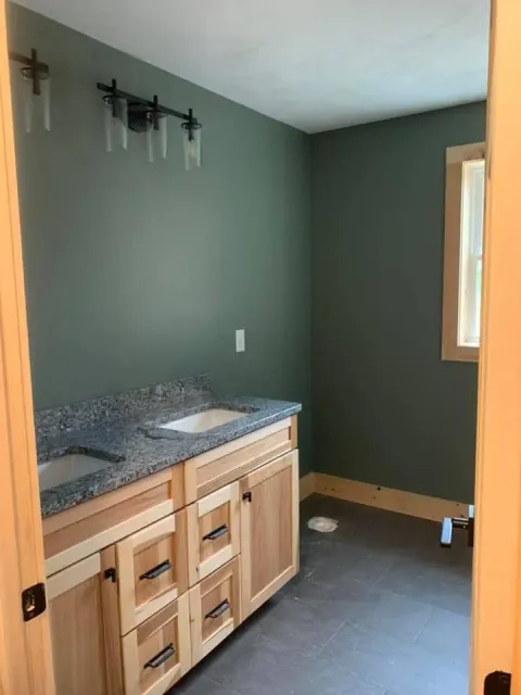 A bathroom with a sink , cabinets and a window.