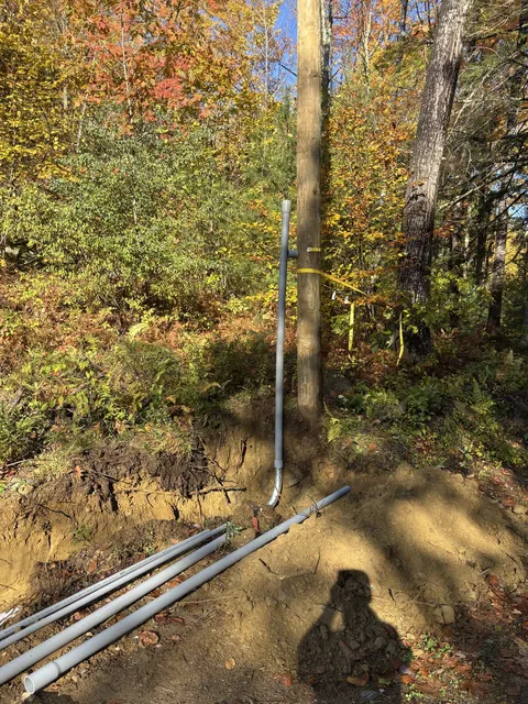 Service riser conduit run up the utility pole with sweeps heading into the trench