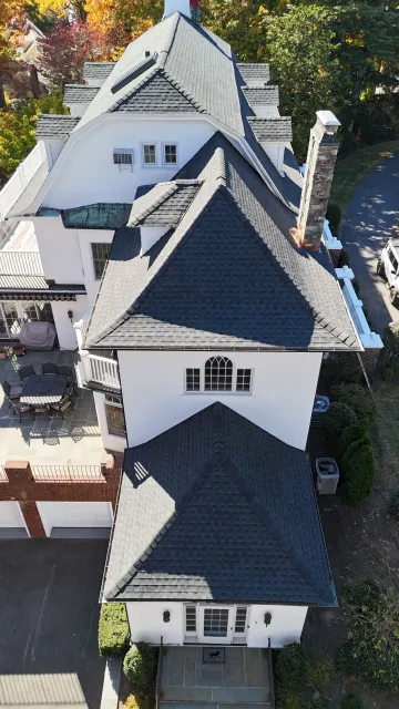 An aerial view of a large white house with a black roof.