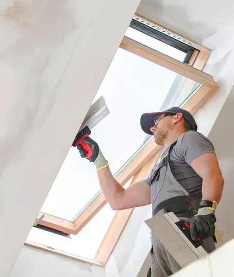 A man is plastering a ceiling with a spatula