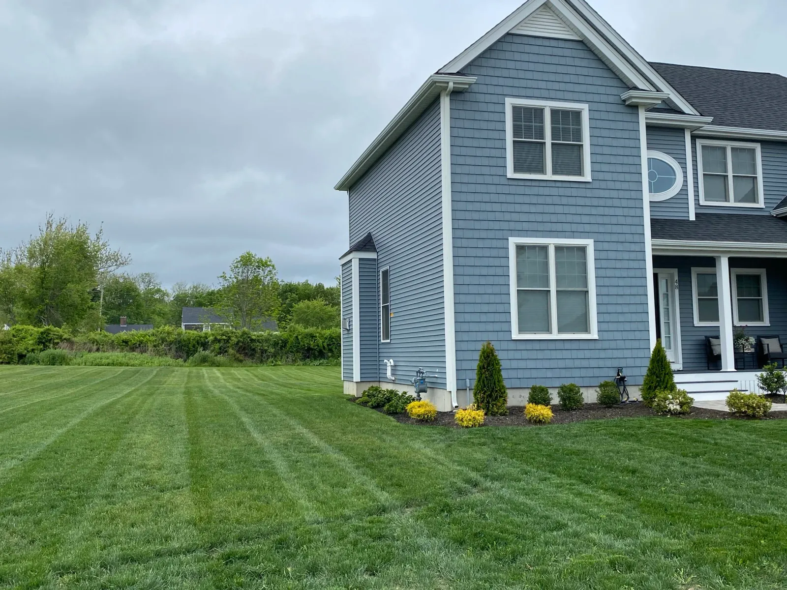 Suburban house with blue siding, manicured lawn, and landscaping in front yard.