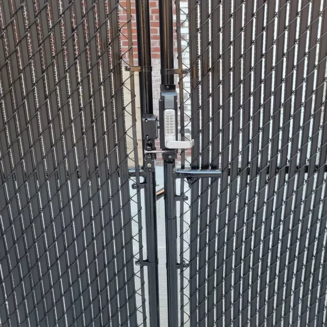Black chain-link gate with privacy slats, secured by a combination lock and latch.