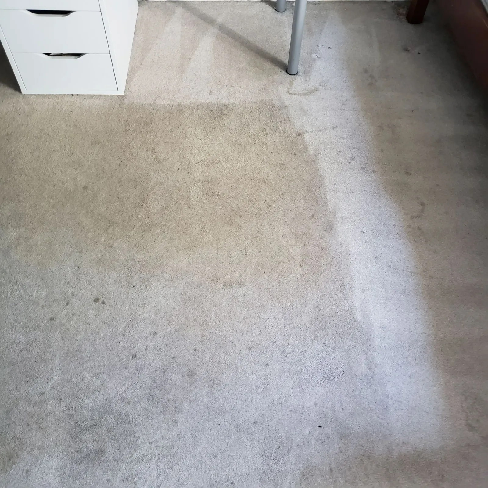 a dirty carpet in a bedroom next to a desk