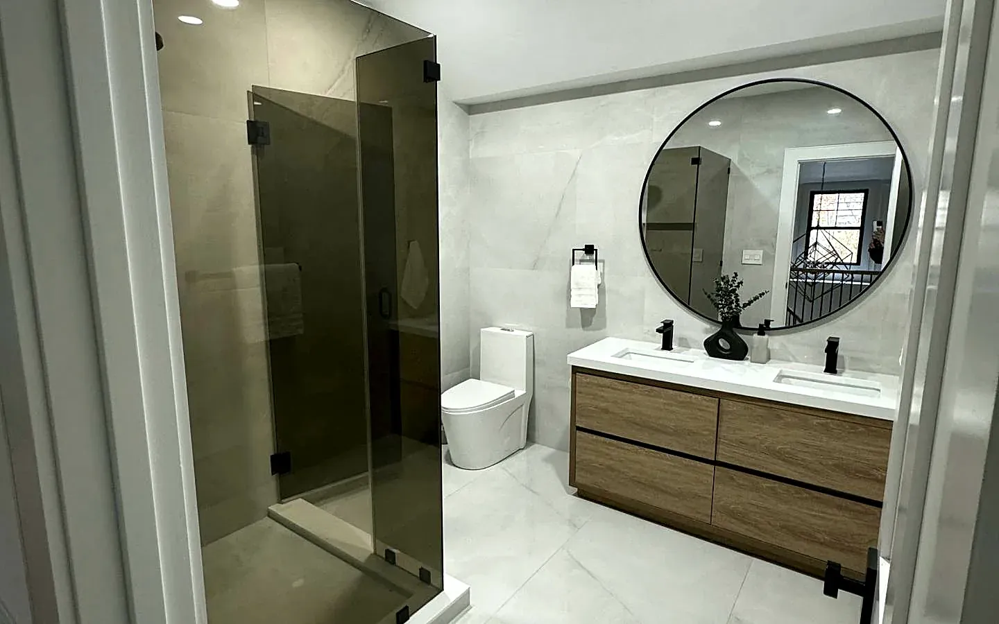 Finished bathroom remodel with walk-in glass shower and floating wood vanity
