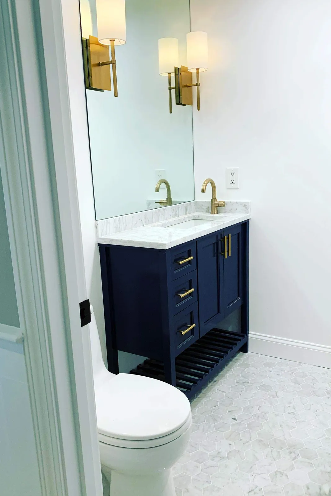 Custom navy bathroom vanity with marble top and open shelf