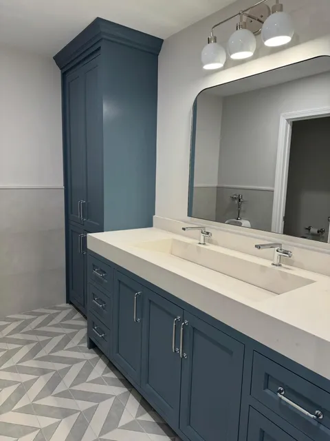 Clean bathroom with navy vanity and polished mirrors