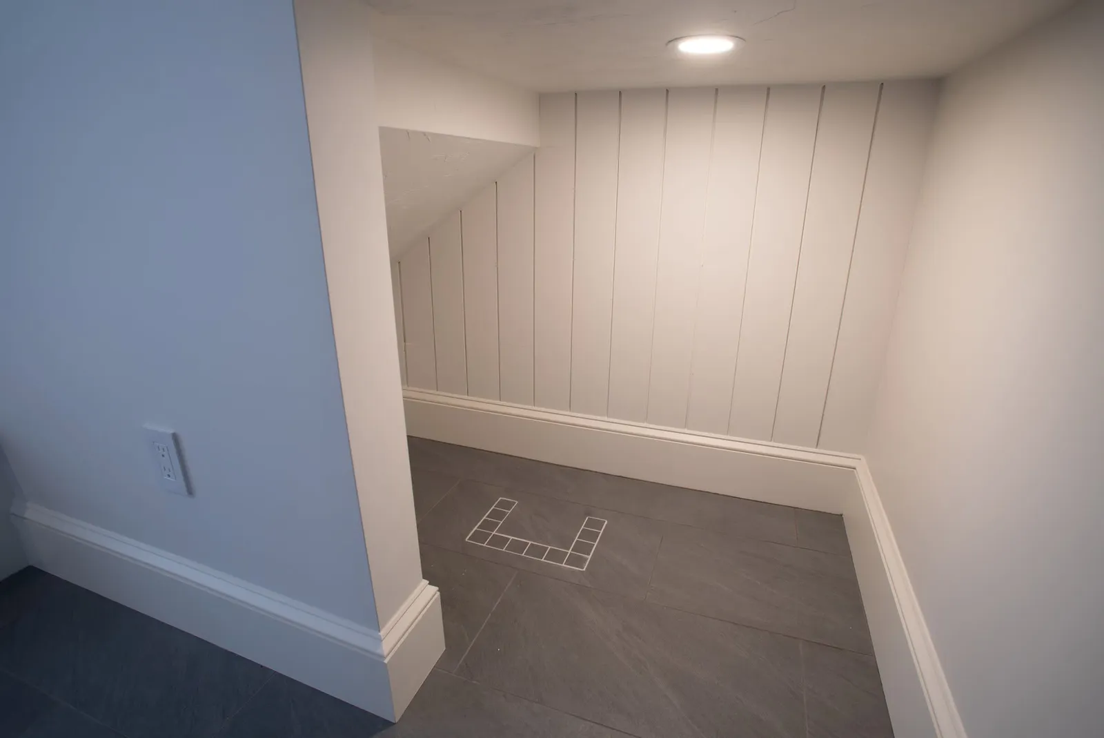 Tiled mudroom nook with beadboard paneling under the stairs