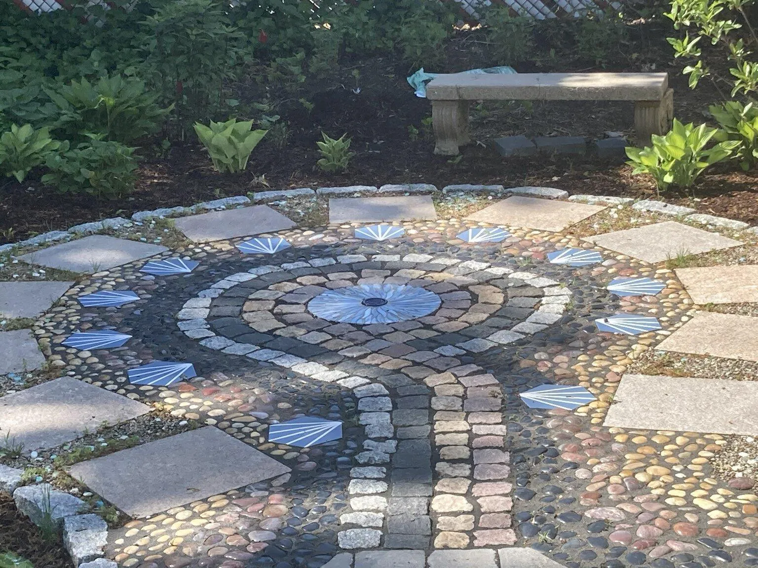 Circular cobblestone and river-rock patio medallion with bluestone pavers