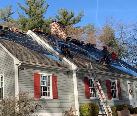 Paul John & Son roofing crew installing CertainTeed Landmark asphalt shingles on a Cape Cod style home — full roof replacement in Greater Boston