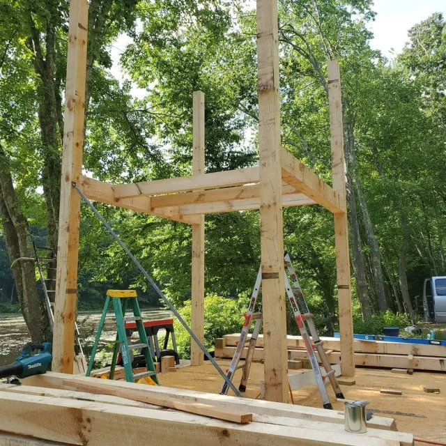 A wooden structure is being built with a ladder in the foreground