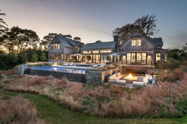 Infinity-edge pool and fire pit terrace set into meadow grasses