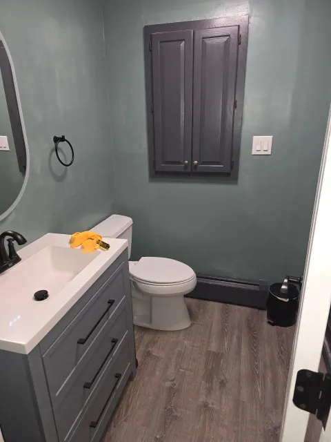 A bathroom with a toilet , sink and mirror.