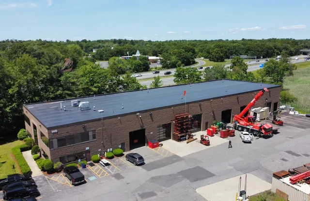 Aerial view of a commercial roof replacement with crane on site