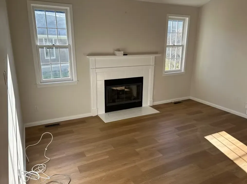 An empty living room with hardwood floors and a fireplace.