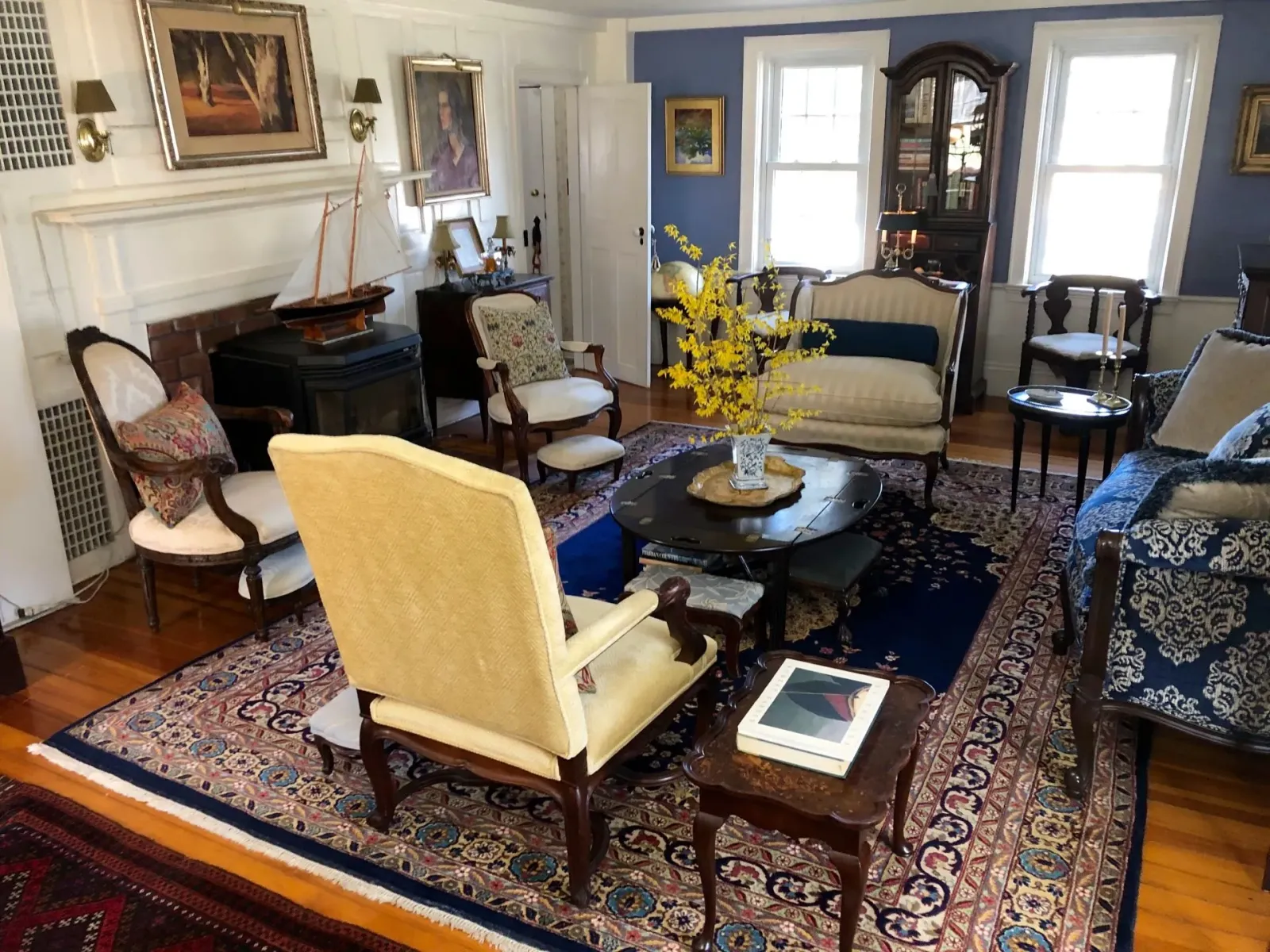 Living room with antique furniture, floral rug, and blue walls.