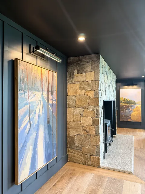 Hardwood floor refinishing showcased in a South Shore home with a stone fireplace, multiple framed artworks, and a warm gallery-style interior.