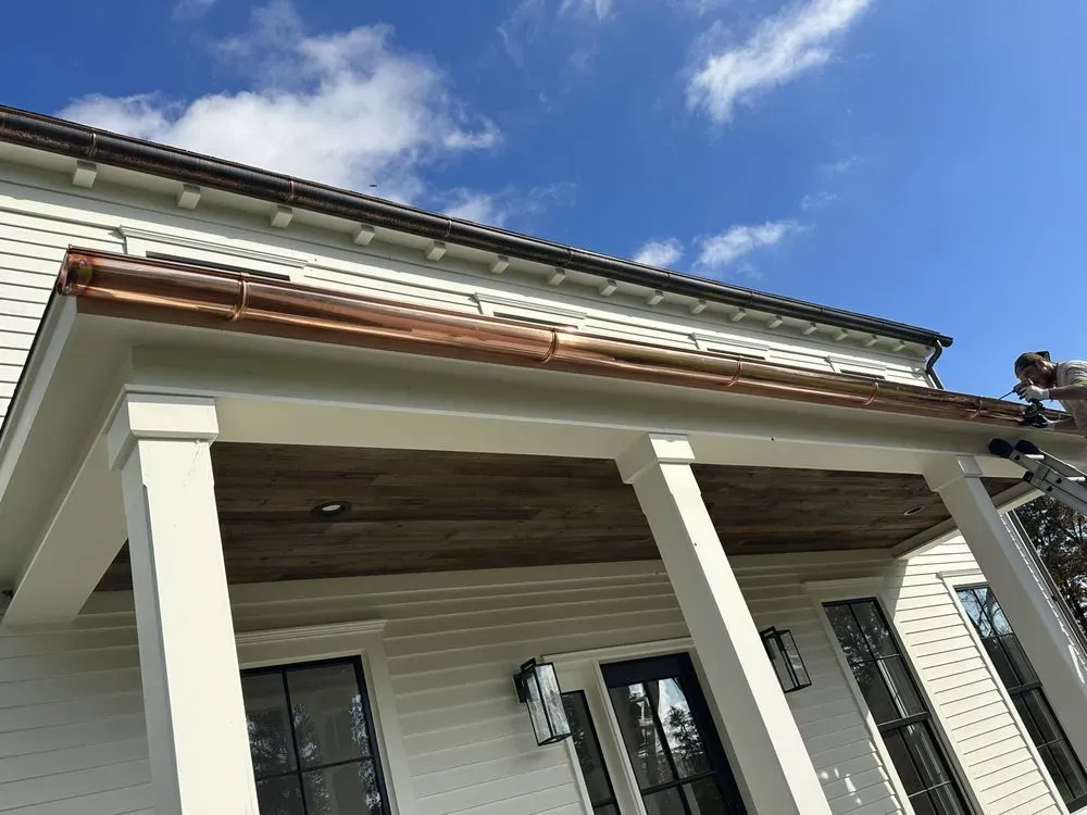 White house porch with columns and a partially finished roof under a blue sky